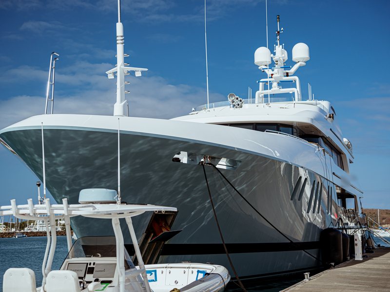 Étrave d'un grand yacht à moteur amarré au ponton visiteurs, à côté de son annexe