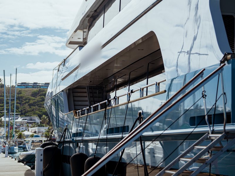 Flanc d'un grand yacht à moteur le long du ponton visiteurs, avec sa passerelle et une borne eau et électricité